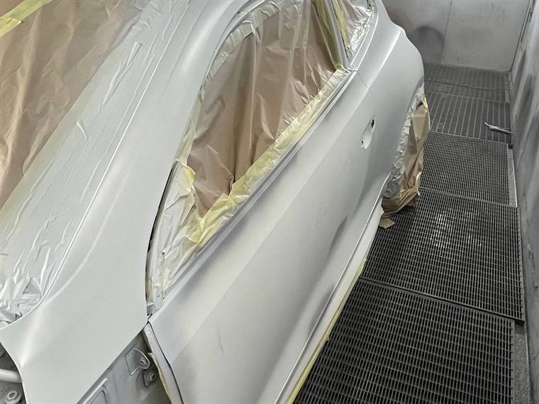 A silver panel masked up inside the spray booth